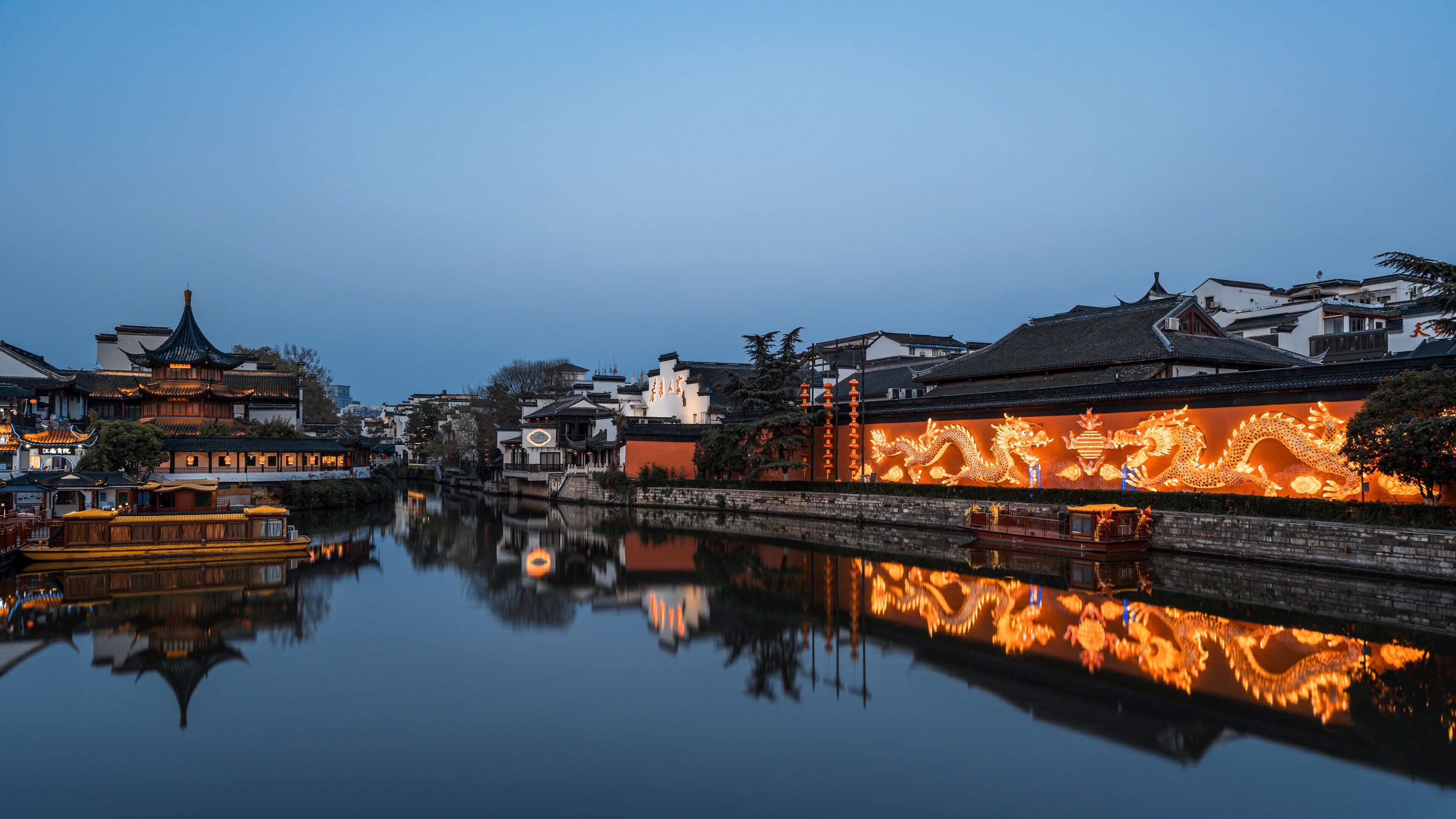 Un pintoresco pueblo acuático chino al anochecer, con edificios iluminados que se reflejan en el agua.