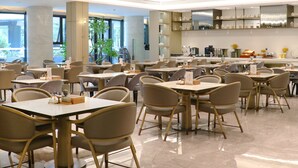 A spacious restaurant with multiple tables and chairs, large windows, and a modern interior design. - Holiday Inn Nanjing South Station by IHG (Nanjing)