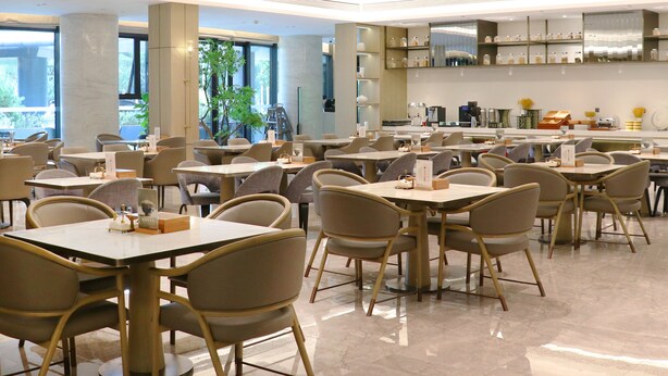 Un ristorante spazioso con numerosi tavoli e sedie, ampie finestre e un design d'interni moderno.