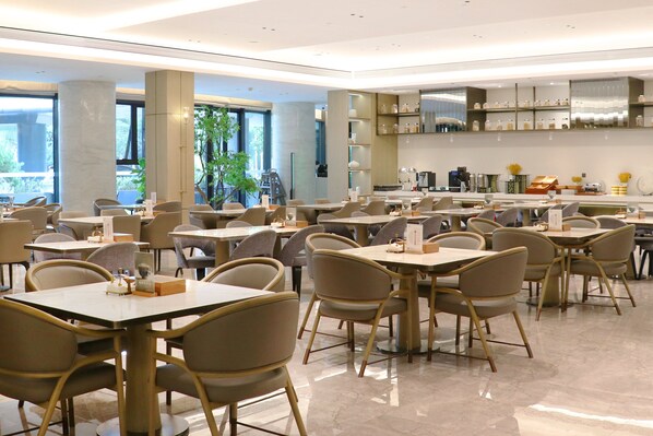 A spacious restaurant with multiple tables and chairs, large windows, and a modern interior design. - Holiday Inn Nanjing South Station by IHG (Nanjing)