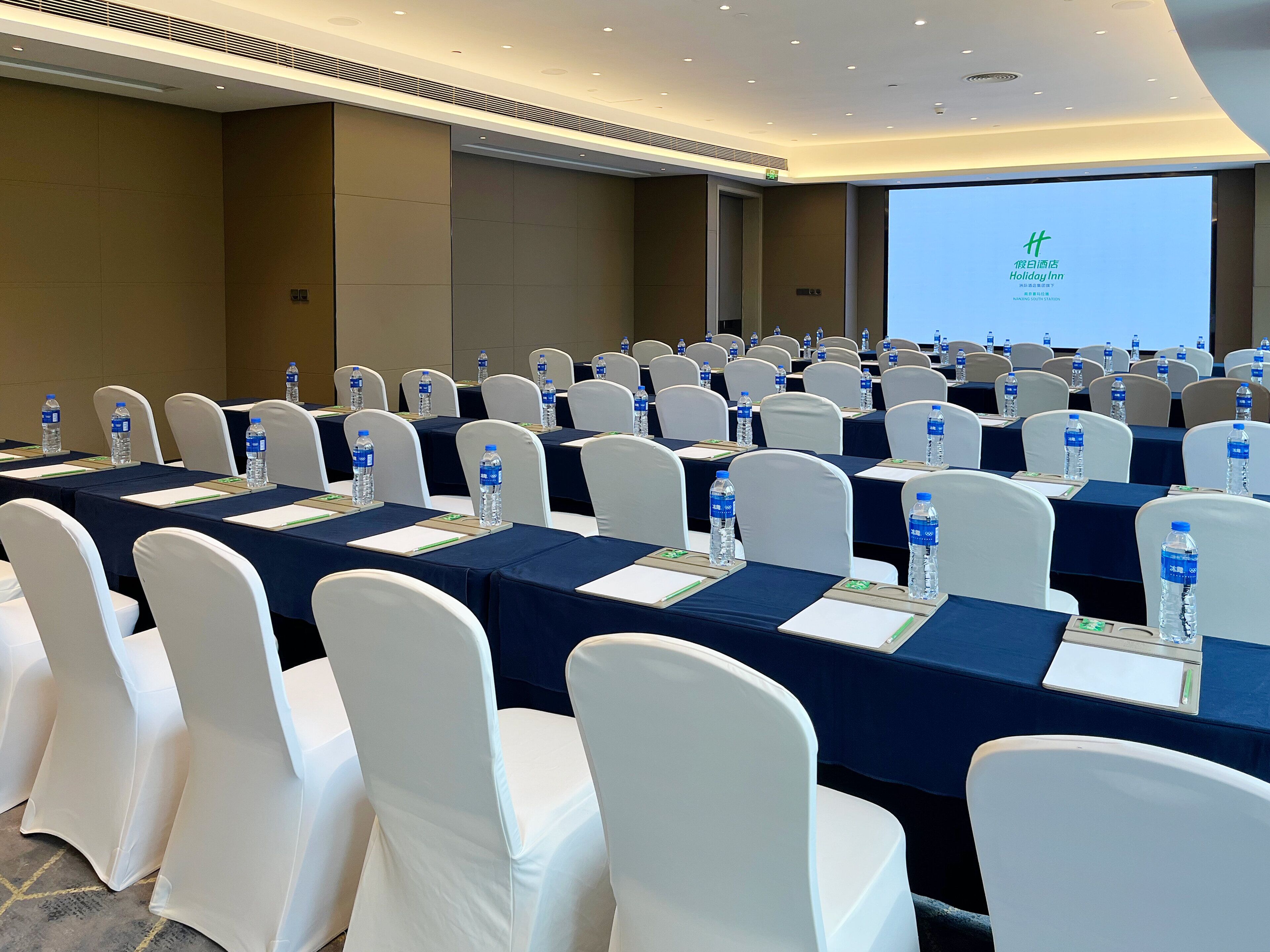 A conference room with rows of tables, chairs, and water bottles.