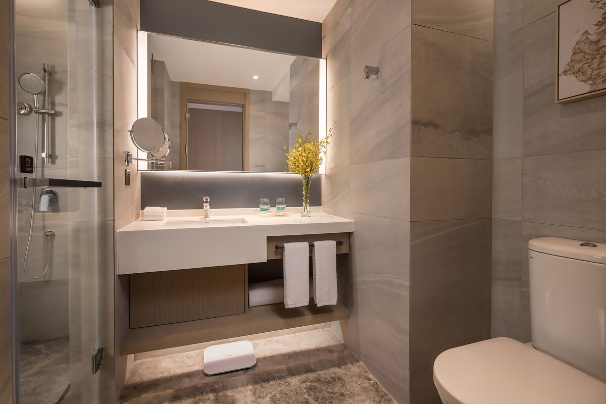 A modern bathroom with a glass-enclosed shower, a white sink with a mirror, and a toilet.