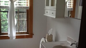 Een badkamer met toilet, wastafel en raam met gordijnen.