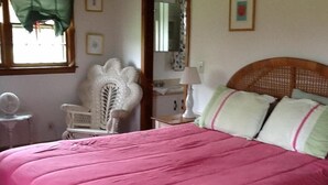 Een slaapkamer met een groot bed, een stoel, een spiegel en een klein tafeltje.