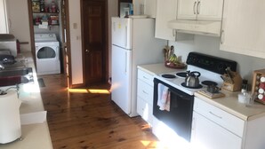 Een kleine keuken met een wasmachine, een koelkast en een fornuis.