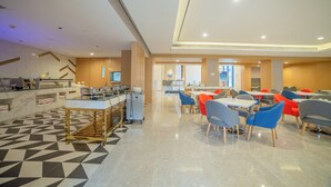 Un comedor moderno con suelo de diseño geométrico, una barra con cafetera y varias mesas con sillas.