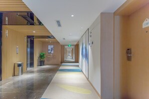 A modern hotel corridor with a long hallway, a potted plant, and a sign indicating room number 1201. - Holiday Inn Express Ya'An City Center by IHG (Ya'an)