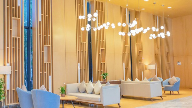 A modern lobby with a sofa, chairs, and a chandelier.