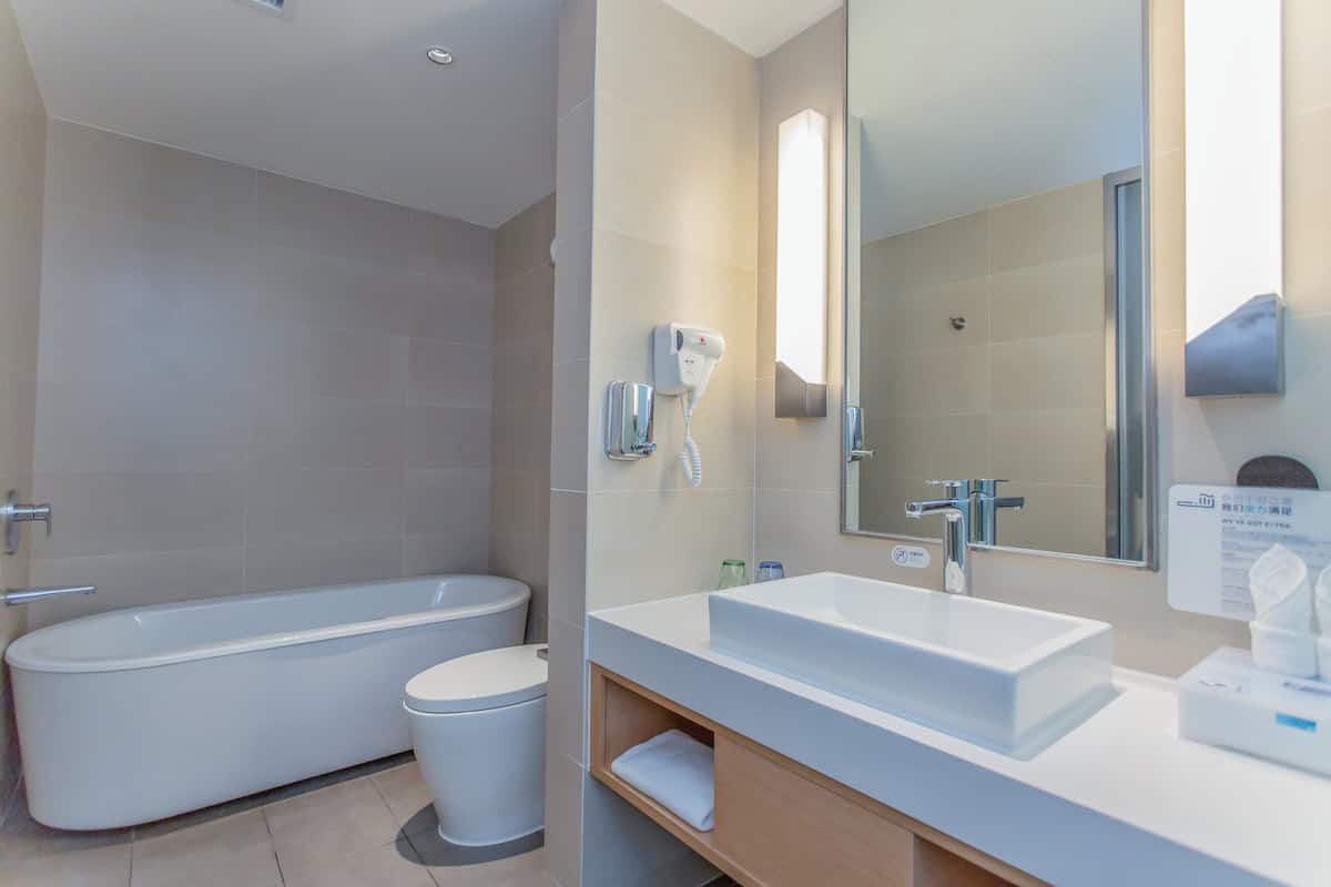 A modern bathroom with a freestanding bathtub, a sink with a mirror, and a hand dryer.
