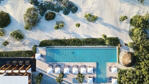 Eine Luftaufnahme eines Resorts mit Swimmingpool, Strand und Palmen.
