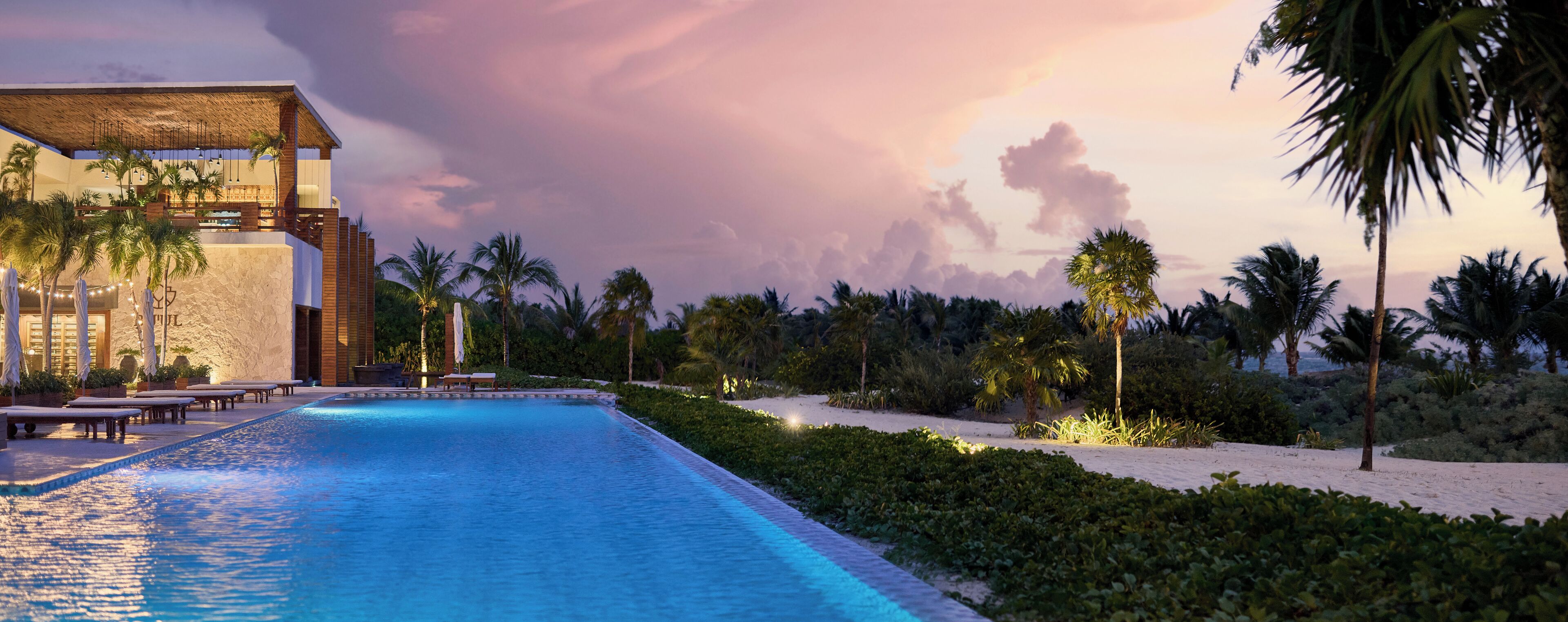 Ein Pool in einem Resort mit Liegestühlen und Palmen.