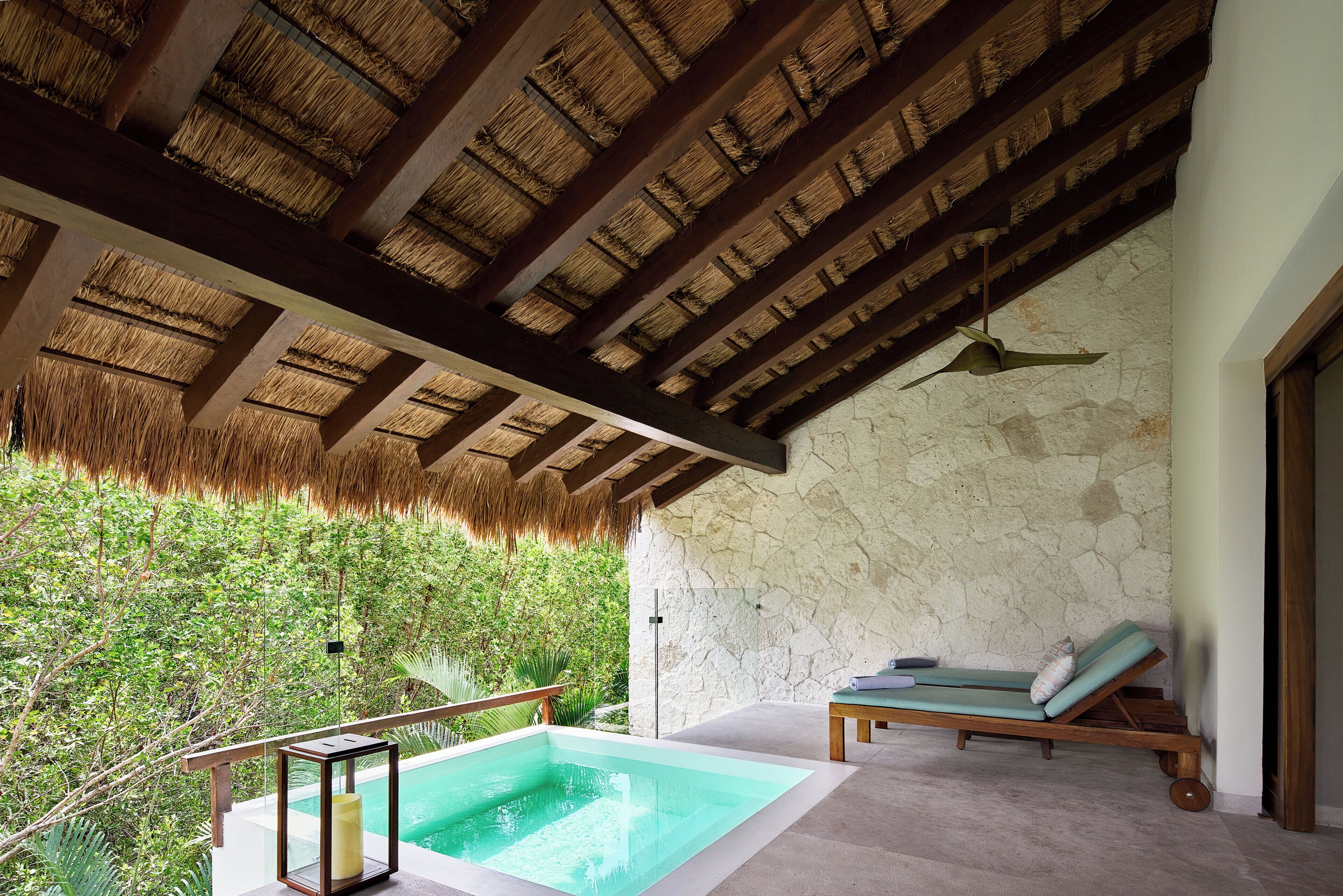 Un espace piscine agrémenté d’un mur en pierre, d’un plafond en bois et d’une chaise longue.