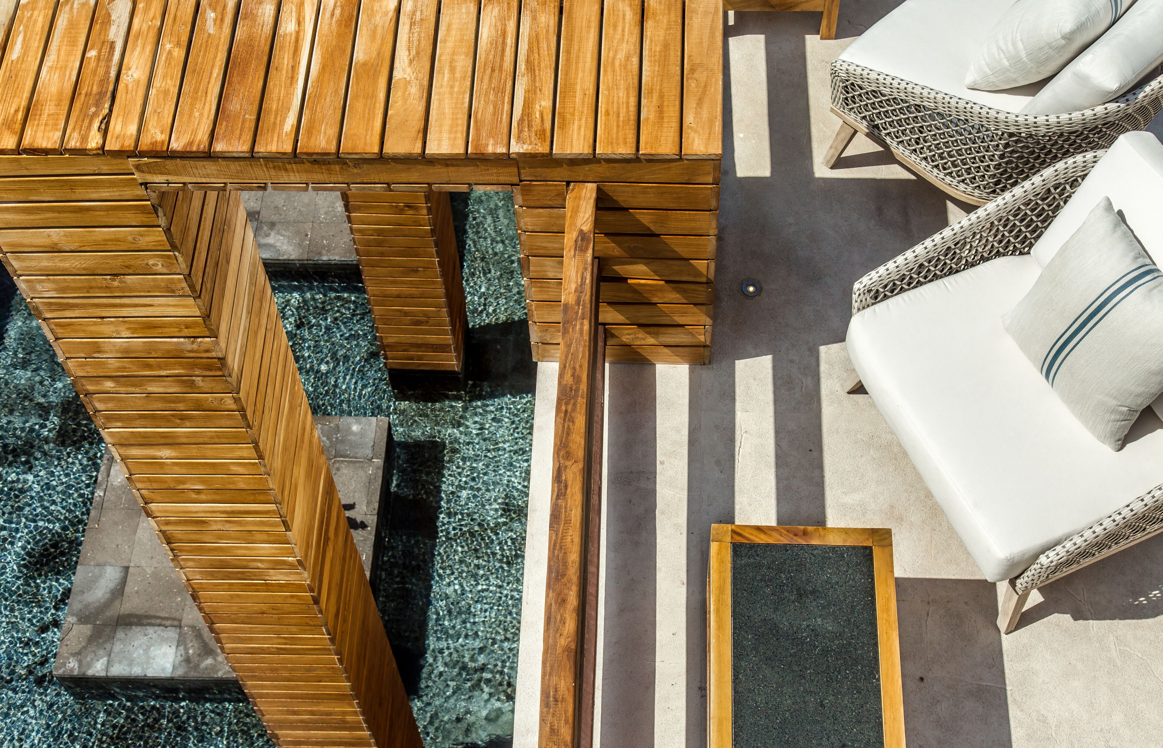 A wooden deck with a table and chairs, a small table, and a white sofa with cushions.