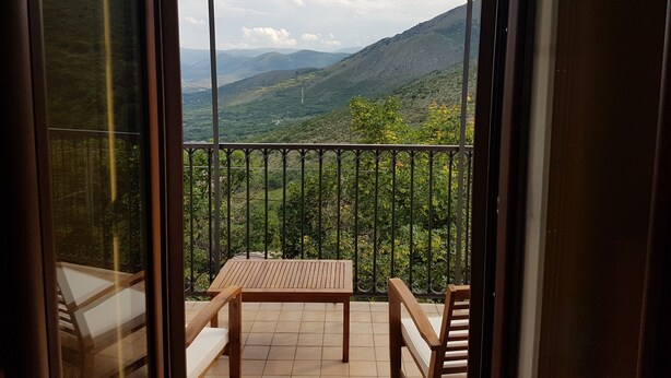 A balcony with a wooden table and chairs, offering a view of a mountainous landscape. - Ofena, Gem in the mountains (Ofena)