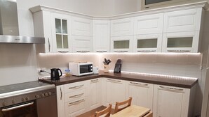 A compact kitchen with white cabinetry, a built-in oven, a microwave, and a wooden dining table with chairs. - Ofena, Gem in the mountains (Ofena)