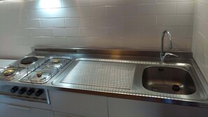 Eine moderne Küche mit Edelstahlherd, Spüle und LED-Beleuchtung unter den Schränken.