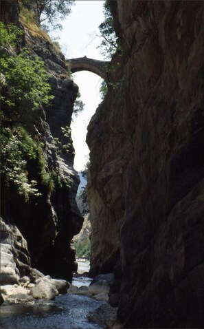 Un canyon étroit, surmonté d’une arche naturelle, et traversé par une rivière.
