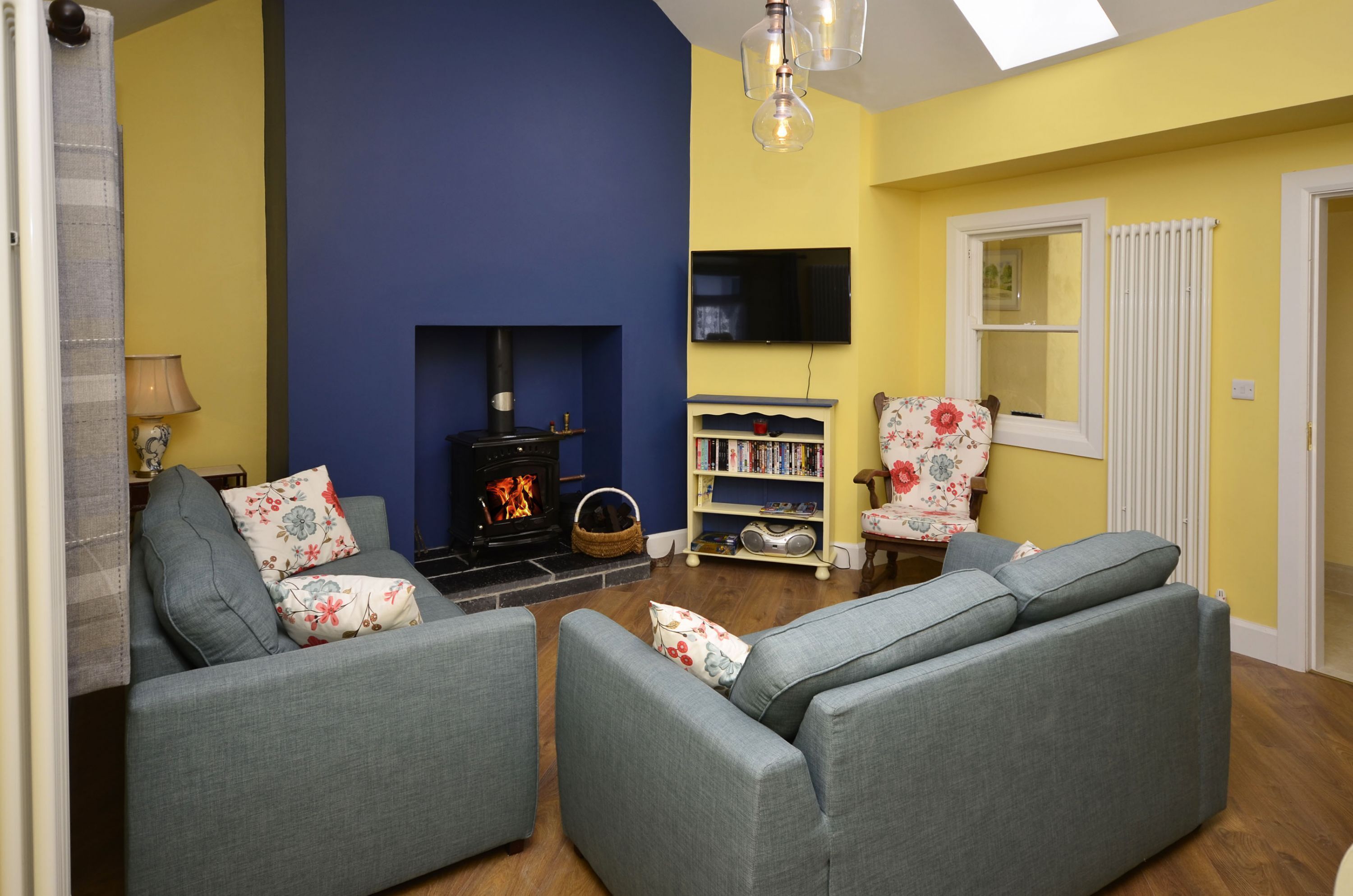 A living room with a fireplace, sofas, a bookshelf, and a television.