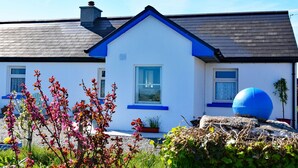 Une maison blanche avec un toit bleu et une cheminée.