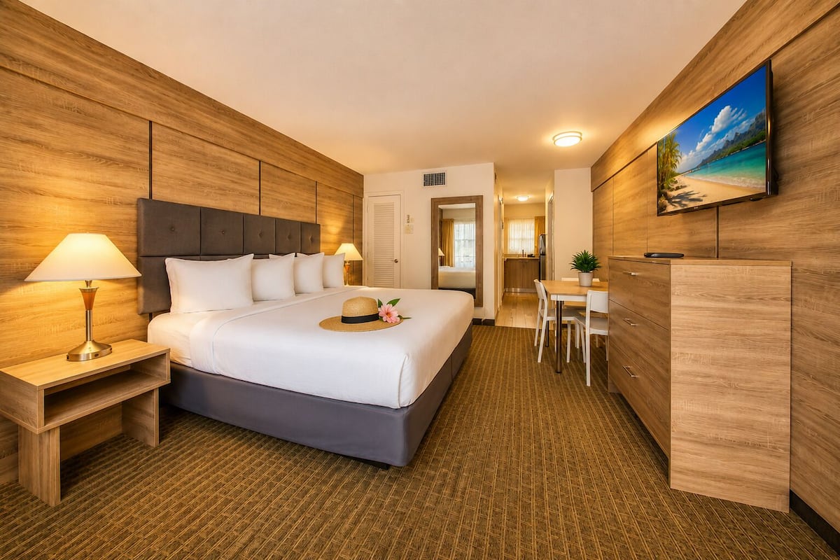 Een hotelkamer met een bed, nachtkastjes, een bureau en een televisie.