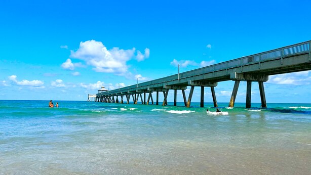 Un muelle que se adentra en el océano bajo cielos despejados.