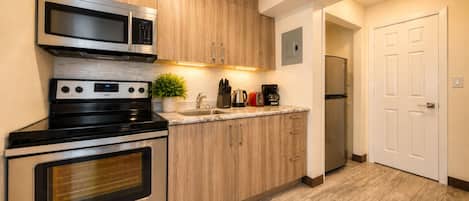 A modern kitchen with stainless steel appliances, wooden cabinets, and a built-in oven.