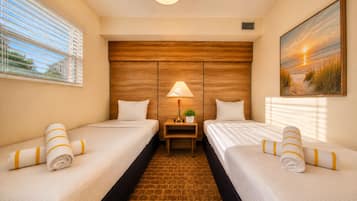 A hotel room with two beds, a nightstand, a lamp, a painting, and a brick-patterned floor.