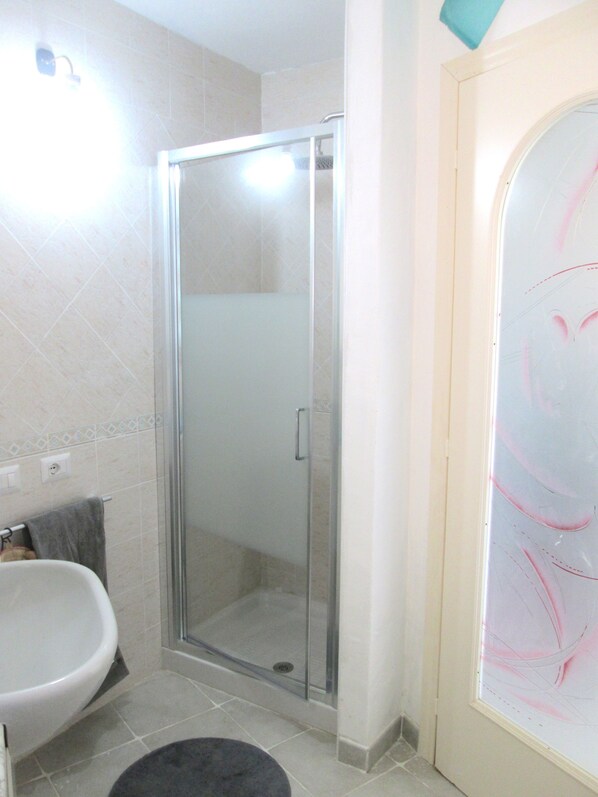A bathroom with a glass-enclosed shower, a white sink, and a towel rack.