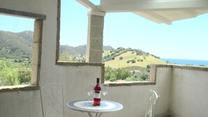 Un balcón con mesa y sillas, una botella de vino y vistas a un paisaje montañoso.