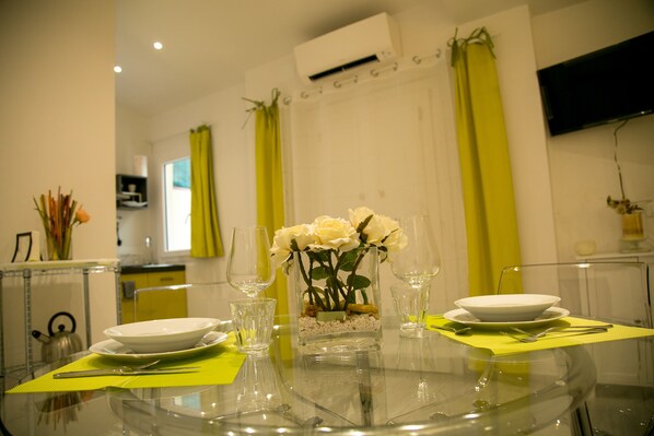 A dining table with a vase of white roses, clear glassware, and plates set for two. - Giripaso Charming Apartment (Firenze)