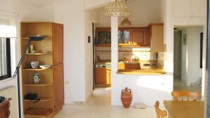 A spacious kitchen with wooden cabinets, a dining table, and a hanging light fixture.