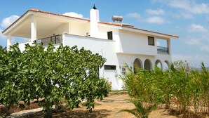 A white building with a tiled roof, a balcony, and a water tank on the roof.