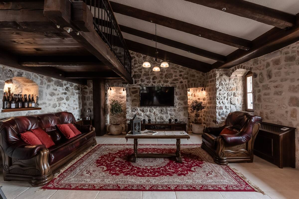 A cozy living room with a stone wall, a leather sofa, a wooden coffee table, and a fireplace.