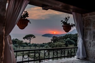 Uma varanda com vista para um pôr do sol sobre a água e uma montanha.