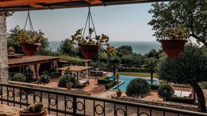 Une terrasse agrémentée de jardinières suspendues, une piscine et une vue sur la mer.