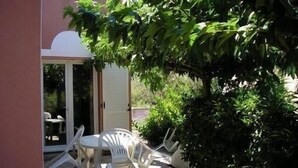 A patio area with a table and chairs, surrounded by greenery. - Independent villa with pool (Agde)