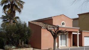 A residential building with a tiled roof, a small porch, and a stone wall. - Independent villa with pool (Agde)