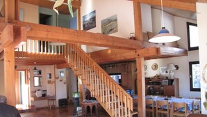 Un vaste espace de vie agrémenté d’un escalier en bois, d’une table à manger avec des chaises et d’un coin salon confortable.