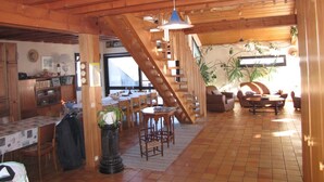 Un vaste espace de vie comprenant un escalier en bois, un coin repas et une cuisine.