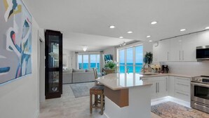 A modern kitchen with a large island, a dining area with a view of the ocean, and a living room with a sofa and a coffee table. - Sterling Sands - Gulf front - Sleeps 8 - Three Bedroom - 3 Bath (Destin)