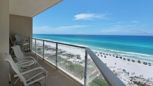 A balcony with white chairs overlooking a beach with umbrellas and a clear blue sky. - Sterling Sands - Gulf front - Sleeps 8 - Three Bedroom - 3 Bath (Destin)