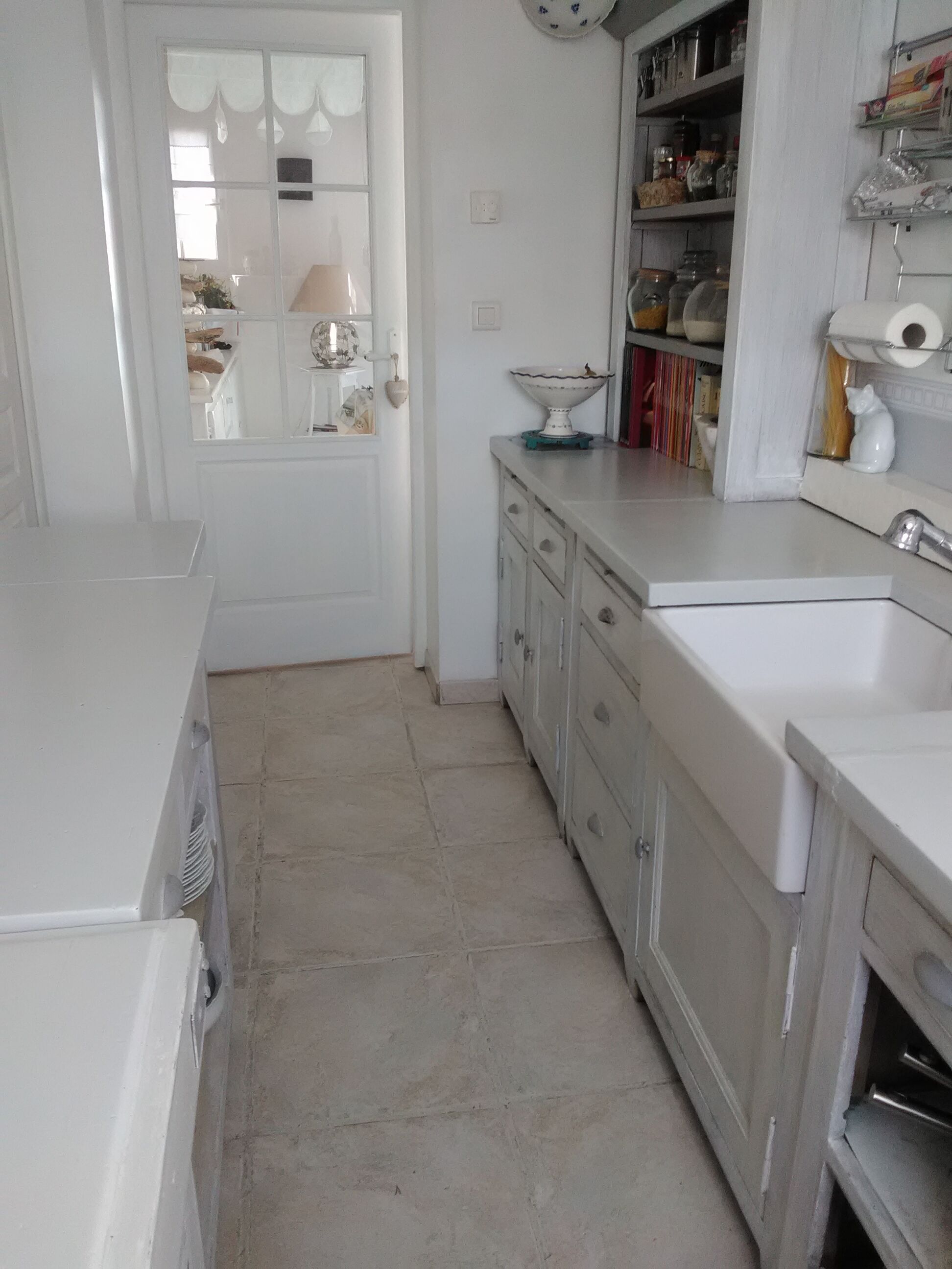 A kitchen with white cabinets, a sink, and a window with curtains.