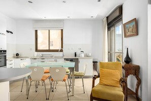 Una cocina moderna con comedor, un ventanal grande y un cuadro en la pared.