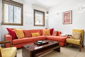 Una sala de estar con un sofá rojo, una mesa de centro de madera y un sillón amarillo.