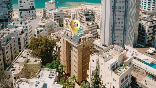 A high-rise building with a rooftop pool, surrounded by other buildings and a beach in the background. - MAMAD Cosy Hideaway steps from Beach by FeelHome (Tel Aviv - Jaffa)