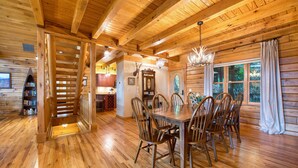 A wooden interior with a dining area, kitchen, and a staircase. - 4 BR Mountain cabin with beautiful long range views in quiet gated community (Maggie Valley)