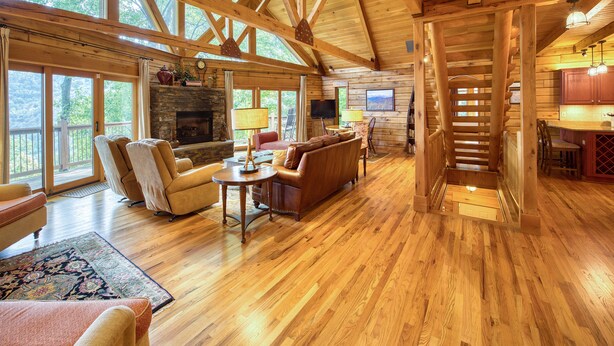 A spacious wooden interior with a fireplace, seating area, and a staircase leading to an upper level. - 4 BR Mountain cabin with beautiful long range views in quiet gated community (Maggie Valley)