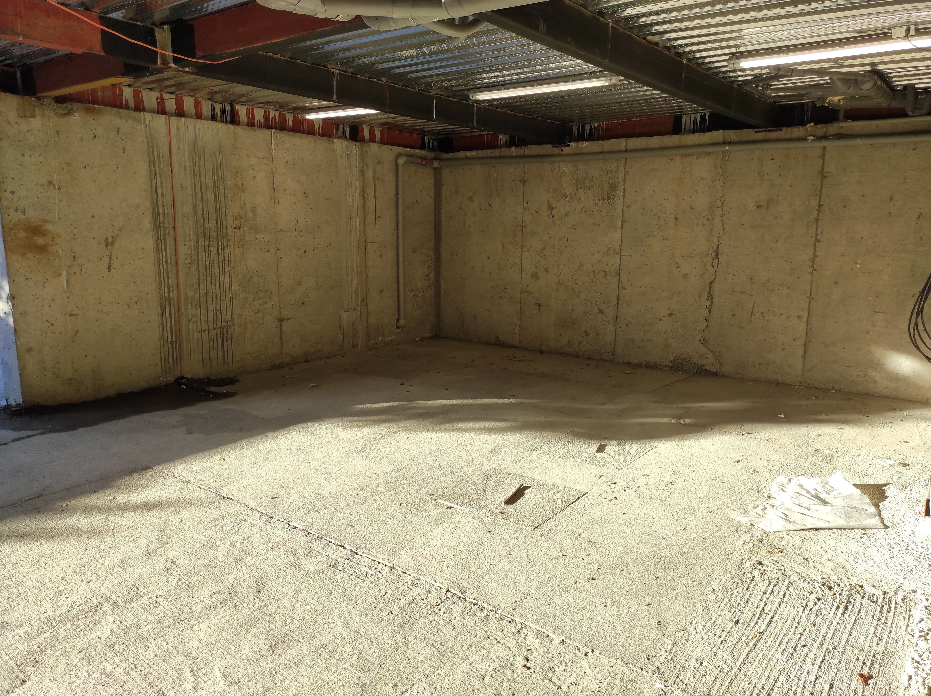 A large, empty room with concrete walls and a metal ceiling.