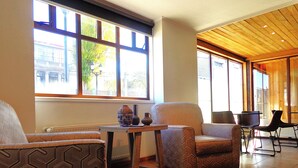 A spacious room with a large window, a wooden ceiling, and a patterned armchair. - Apart Hotel Endurance (Punta Arenas)