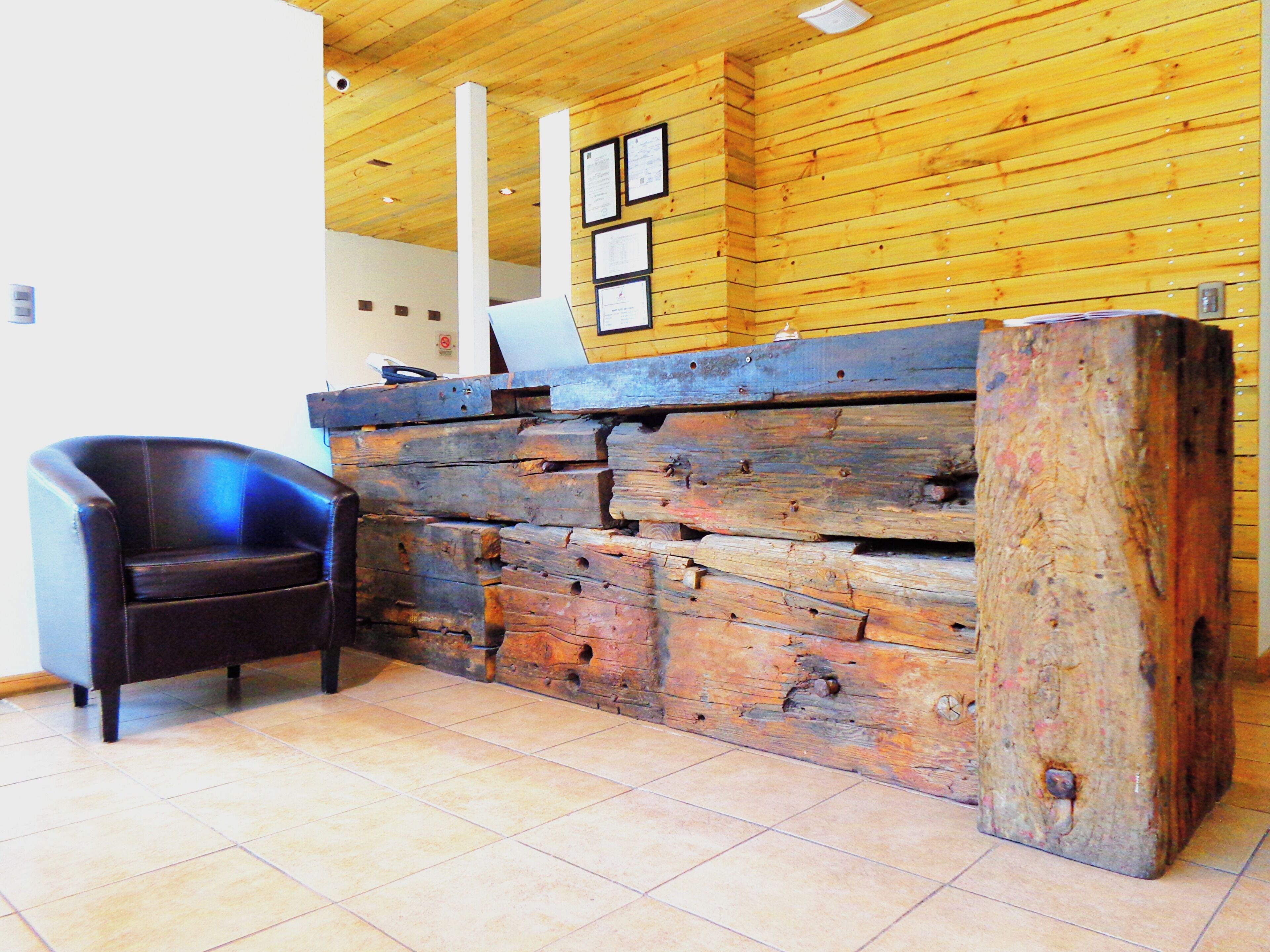 A reception desk with a wooden backdrop, a black leather chair, and a tiled floor.